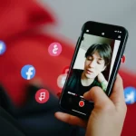 A person captivated by a short video on their phone, 35mm portrait, depth of field, showing blurred social media icons.