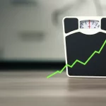 Concetto di salute e monitoraggio del peso corporeo: una bilancia medica analogica al centro, affiancata da un grafico a linea astratto che mostra fluttuazioni verso l'alto e verso il basso, sfondo neutro e pulito con leggera sfocatura, obiettivo 50mm prime, luce da studio controllata e morbida, stile fotorealistico.