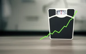 Concetto di salute e monitoraggio del peso corporeo: una bilancia medica analogica al centro, affiancata da un grafico a linea astratto che mostra fluttuazioni verso l'alto e verso il basso, sfondo neutro e pulito con leggera sfocatura, obiettivo 50mm prime, luce da studio controllata e morbida, stile fotorealistico.