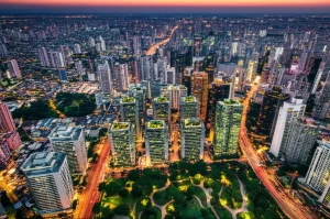 Immagine aerea di una metropoli del Sud del Mondo al tramonto, dove corridoi verdi lussureggianti e parchi urbani si intrecciano con gli edifici, simboleggiando l'integrazione delle soluzioni basate sulla natura. Obiettivo grandangolare 20mm, lunga esposizione per scie luminose del traffico, messa a fuoco nitida sull'intera skyline, colori caldi e contrastati.