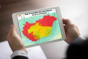 Mappa di vulnerabilità delle acque sotterranee del sud-est dell'Ungheria, visualizzata su un tablet tenuto da mani esperte, con sovrapposte aree colorate (rosso per alta vulnerabilità, giallo per moderata) su una base topografica. Profondità di campo ridotta per sfocare lo sfondo, obiettivo 35mm, illuminazione da studio controllata.