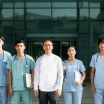 A diverse group of nursing students, looking engaged and slightly apprehensive but hopeful, stand outside a modern, welcoming hospital entrance. A friendly instructor is with them. Portrait photography, prime lens 35mm, natural morning light, depth of field, creating a positive and inviting atmosphere.