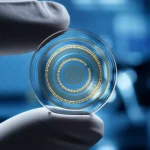 Immagine macro estremamente dettagliata di una lente a contatto bimodale trasparente e flessibile, con sottili circuiti dorati a spirale visibili sulla sua superficie. La lente è tenuta tra due dita guantate in un ambiente di laboratorio high-tech, con luci soffuse che ne esaltano la texture. Lunghezza focale 85mm, alta definizione, illuminazione controllata per enfatizzare la tecnologia.