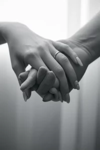 Un'immagine simbolica che rappresenta la speranza e il miglioramento della qualità della vita dopo un trattamento oncologico. Potrebbe essere una mano che ne stringe un'altra con delicatezza in un ambiente medico sereno, o un paziente che sorride guardando fuori da una finestra. Obiettivo prime 50mm, luce soffusa, profondità di campo, colori tenui per un effetto emotivo e rassicurante, bianco e nero film.