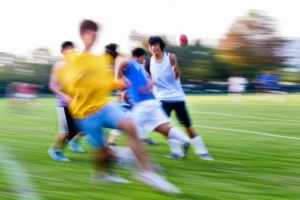 Energetic college students participating in outdoor sports, telephoto zoom, 150mm, fast shutter speed, movement tracking, conveying joy and well-being.