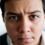 A close-up portrait of a young person looking tired but determined, 35mm portrait lens, depth of field, representing the struggle with chronic fatigue in sickle cell disease.