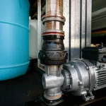 Photorealistic image of a self-priming pump connected to a transparent pipe and water tank, showing water level, wide-angle lens, 24mm, sharp focus, controlled lighting.