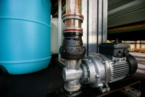 Photorealistic image of a self-priming pump connected to a transparent pipe and water tank, showing water level, wide-angle lens, 24mm, sharp focus, controlled lighting.