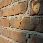 Primo piano di un muro di mattoni antico in una casa rurale cinese, con l'intelligenza artificiale che evidenzia digitalmente aree di danno come ingiallimento e piccole crepe. Macro lens, 85mm, high detail, luce laterale per enfatizzare la texture e il deterioramento.