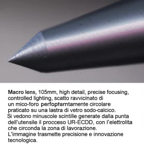 Macro lens, 105mm, high detail, precise focusing, controlled lighting, scatto ravvicinato di un micro-foro perfettamente circolare praticato su una lastra di vetro sodo-calcico. Si vedono minuscole scintille generate dalla punta dell'utensile durante il processo UR-ECDD, con l'elettrolita che circonda la zona di lavorazione. L'immagine trasmette precisione e innovazione tecnologica.