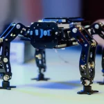 Un robot LISA (Lizard-Inspired Single-Actuated) in un laboratorio high-tech, illuminazione controllata per evidenziare i dettagli del meccanismo a quattro barre e delle zampe a forma di artiglio. Obiettivo macro 85mm, alta definizione, focus preciso sui giunti e sui link del robot, sfondo leggermente sfocato per enfatizzare il soggetto.