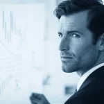 Fotografia ritratto con obiettivo da 35mm, profondità di campo, bicromia blu e grigio, che mostra un imprenditore determinato mentre osserva pensieroso un diagramma complesso che rappresenta le dinamiche di mercato e i percorsi di innovazione per una PMI.