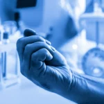 Una mano forte e curata, simbolo di salute e vitalità, con sullo sfondo sfocato elementi che richiamano la ricerca medica e il benessere, 35mm portrait, duotone blu e grigio, profondità di campo.