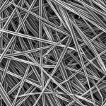 Fotografia macro di un campione di nanocomposito Elium® nero opaco rinforzato con nanofibre. Si intravedono le fibre sottili integrate nella matrice polimerica. Lente macro 60mm, alta definizione, illuminazione laterale controllata per enfatizzare la texture superficiale composita, messa a fuoco precisa.