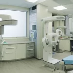 Wide-angle landscape, 20mm lens, vista panoramica all'interno di una clinica di implantologia dentale moderna e luminosa, che mostra attrezzature avanzate come scanner CBCT e setup chirurgico, messa a fuoco nitida, rappresentando l'ambiente per procedure avanzate di rigenerazione ossea.