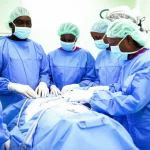 Un team di medici e infermieri tanzaniani collabora attivamente in una sala operatoria moderna e luminosa di un ospedale pubblico, fotografia di reportage, obiettivo prime da 50mm, luce diffusa, espressioni di concentrazione e speranza, dettagli nitidi sulle attrezzature mediche.