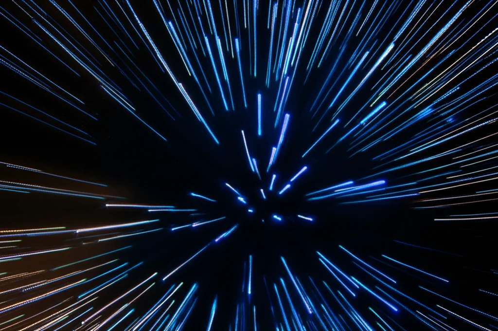 Visualizzazione artistica di uno sciame di particelle luminose che si muovono in modo coordinato in uno spazio tridimensionale astratto, convergendo verso un punto luce che rappresenta la soluzione ottimale. Alcune particelle formano gruppi distinti, suggerendo la strategia multi-sciame. Wide-angle lens, 10mm, long exposure times per creare scie luminose, sharp focus sul punto di convergenza, con un effetto bokeh sullo sfondo per dare profondità.