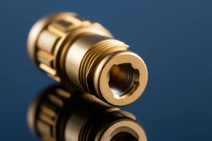 Fotografia macro di un pilastro implantare in titanio dorato appoggiato su un piano riflettente, con focus selettivo sulla connessione interna, illuminazione da studio per esaltare la texture metallica, focale 100mm, alta definizione dei dettagli.