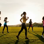 Scatto dinamico di un gruppo diversificato di persone (asiatici cinesi e malesi) che partecipano con entusiasmo a un'attività sportiva all'aperto, come una corsa comunitaria o una sessione di yoga in un parco panoramico al tramonto, fotografia sportiva, obiettivo zoom 70-200mm, velocità dell'otturatore rapida, catturando movimento ed emozione, colori caldi del tramonto.