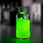 Immagine fotorealistica di campioni di fosfori Ba2Cd(BO3)2 drogati con disprosio (giallo brillante) e terbio (verde brillante) che emettono luce sotto eccitazione UV, disposti su un tavolo da laboratorio. Macro lens, 100mm, high detail, precise focusing, controlled lighting, con un leggero effetto bokeh sullo sfondo per mettere a fuoco i campioni.