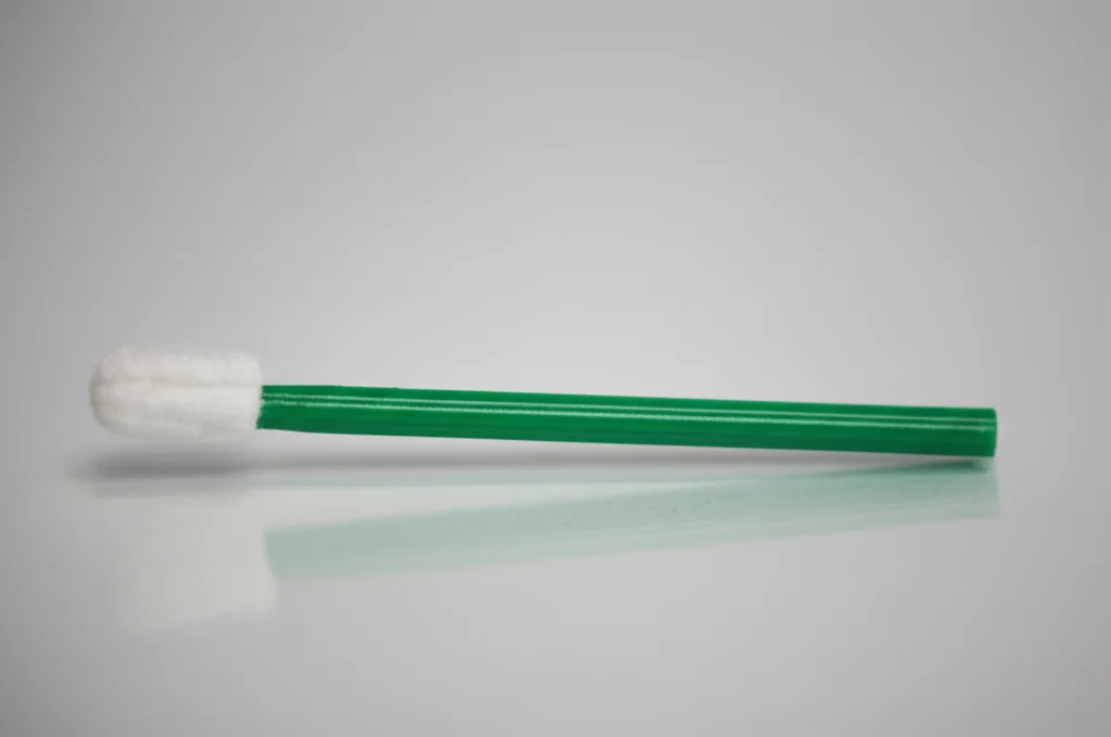 Scatto di lenti macro di un kit di auto-campionamento HPV (pennello e fiala) disposto su una superficie pulita e semplice. Lenti macro da 60-105 mm, dettagli elevati, messa a fuoco precisa, illuminazione controllata, enfatizzando la semplicità e l'accessibilità del kit.