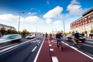 Fotografia grandangolare, 15mm, di una moderna superstrada ciclabile ben progettata a Copenaghen, separata dal traffico, con ciclisti in movimento (leggero motion blur), cielo azzurro con nuvole soffici, luce del tardo pomeriggio, focus nitido, colori vivaci.
