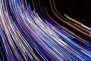 Una visualizzazione dati astratta e dinamica con linee luminose e particelle che fluiscono tra due stati grafici, simboleggiando una transizione animata. Telephoto zoom 100mm, fast shutter speed, movement tracking, colori brillanti su sfondo scuro.