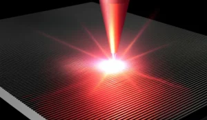 Visualizzazione artistica e fotorealistica di un fascio laser a femtosecondi che interagisce con un materiale 2D (NbOI2) creando nano-scanalature (NGA) con super-risoluzione (λ/73). Obiettivo macro, 100mm, dettaglio elevato, illuminazione drammatica che evidenzia le nanostrutture e l'interazione luce-materia in aria ambiente.