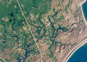 Veduta aerea satellitare di un paesaggio diversificato che mostra aree verdi lussureggianti e zone aride colpite dalla siccità, con fiumi e laghi visibili. Obiettivo grandangolare 14mm, alta risoluzione, luce naturale del giorno, per illustrare il concetto di valutazione della siccità basata su satellite e l'integrazione di AHP e logica fuzzy.