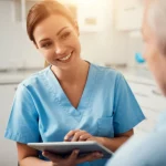 A compassionate dental nurse in a bright, modern dental clinic is engaged in a supportive conversation with a patient. The nurse is using a tablet to show information, and the patient looks receptive. Portrait photography, 35mm lens, depth of field, warm and inviting lighting.