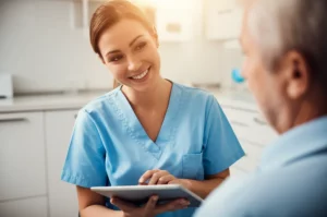 A compassionate dental nurse in a bright, modern dental clinic is engaged in a supportive conversation with a patient. The nurse is using a tablet to show information, and the patient looks receptive. Portrait photography, 35mm lens, depth of field, warm and inviting lighting.