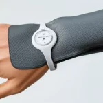 Immagine concettuale di un sistema indossabile multifunzionale per la termoterapia dell'artrite, che mostra la sua flessibilità e integrazione con il corpo umano. Lente prime 50mm, profondità di campo, illuminazione da studio che evidenzia la texture del materiale e i componenti elettronici flessibili, sfondo neutro per concentrarsi sul prodotto.