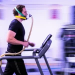 Photorealistic image of a person undergoing a cardiopulmonary exercise test on a treadmill, wearing a mask and connected to equipment, motion photography, 200mm telephoto zoom, fast shutter speed, movement tracking, illustrating the study's methodology.