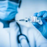 Un medico con mascherina protettiva e guanti tiene in mano una siringa con il vaccino COVID-19, pronto per l'inoculazione, simboleggiando la speranza e la ricerca scientifica contro il Long COVID. Portrait photography, prime lens, 35mm, depth of field, duotone blu e bianco per un effetto pulito e medico.