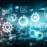 Un'immagine concettuale che rappresenta l'intersezione tra industria manifatturiera, gestione del cambiamento e strumenti digitali. Ingranaggi stilizzati si trasformano in icone digitali luminose, collegate da un flusso di dati. Obiettivo grandangolare da 24mm, illuminazione dinamica e moderna, con profondità di campo per mettere a fuoco sia gli ingranaggi che le icone.