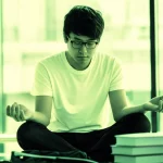 Fotografia di uno studente universitario cinese, specializzando in inglese, che pratica mindfulness in un ambiente accademico sereno, con libri e luce naturale, utilizzando un obiettivo da 35mm per un ritratto con profondità di campo, evocando resilienza e speranza accademica. Duotone verde e ocra per un senso di crescita e calore.