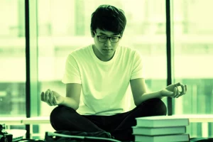 Fotografia di uno studente universitario cinese, specializzando in inglese, che pratica mindfulness in un ambiente accademico sereno, con libri e luce naturale, utilizzando un obiettivo da 35mm per un ritratto con profondità di campo, evocando resilienza e speranza accademica. Duotone verde e ocra per un senso di crescita e calore.