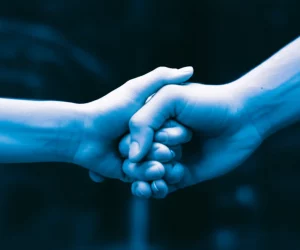 A 35mm portrait, duotone blue and grey, of two hands clasped together, symbolizing a shared relationship and project, with depth of field.
