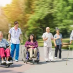 Immagine fotorealistica di un gruppo eterogeneo di adulti con diverse disabilità che partecipano con gioia a varie attività fisiche in un parco pubblico ben curato in Cina. Alcuni sono in sedia a rotelle e fanno esercizi di gruppo, altri camminano con ausili, un altro fa tai chi. Un professionista sanitario sorridente osserva discretamente in secondo piano. Obiettivo grandangolare, 15mm, per catturare l'ampiezza della scena e l'inclusività, luce naturale brillante, effetto di leggero motion blur per suggerire movimento e dinamismo.