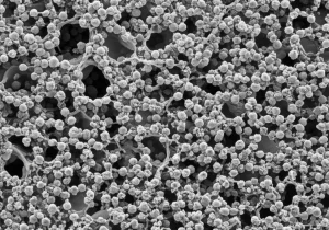Immagine fotorealistica di un campione di materiale granulare umido analizzato con microtomografia a raggi X, evidenziando la complessa interazione tra particelle solide e fase liquida, con ponti liquidi visibili, illuminazione da studio, obiettivo macro 100mm, alta definizione e focus preciso sulla microstruttura.