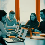 Un gruppo eterogeneo di studenti universitari discute animatamente attorno a un tavolo, alcuni con laptop aperti che mostrano interfacce AI, altri con libri. L'atmosfera è un misto di preoccupazione e curiosità. Prime lens, 35mm, depth of field, luce naturale da una grande finestra, duotone ciano e arancione per un contrasto moderno.