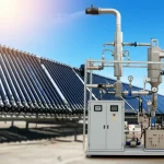Un impianto solare termico all'avanguardia con una serie di collettori a tubi sottovuoto che riflettono un cielo azzurro e un sole brillante, collegati attraverso tubazioni isolate a un'unità ORC (Organic Rankine Cycle) compatta e moderna, visibile in primo piano. L'unità ORC presenta componenti metallici lucidi, indicatori di pressione e temperatura. Telephoto zoom, 150mm, fast shutter speed, sharp focus sull'unità ORC con i collettori leggermente sfocati sullo sfondo per dare profondità, luce solare diretta che crea giochi di luce.