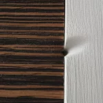 Immagine macro ad alta definizione di due materiali con texture diverse, uno con venature direzionali (ortotropo) e uno liscio (isotropo), che entrano in contatto sotto una pressione visibile, illuminazione da studio controllata, obiettivo macro 90mm, con un leggero effetto di deformazione nel punto di contatto.