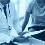 Primo piano di un medico specialista in gastroenterologia che consulta un paziente in un ambiente clinico moderno e rassicurante, discutendo opzioni di trattamento. Prime lens 35mm, depth of field, luce naturale soffusa, duotone blu e grigio per un'atmosfera professionale e calma.