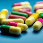 Immagine concettuale fotorealistica: capsule di probiotici colorate (simbolo di aiuto) accanto a simboli stilizzati di allergeni alimentari comuni (arachidi, latte, uova) protetti da uno scudo trasparente (simbolo di immunoterapia e sicurezza). Focus nitido sulle capsule, sfondo medico leggermente sfocato, illuminazione da studio, 35mm prime lens.