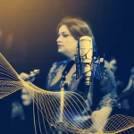 Primo piano di un microfono da studio professionale davanti a un cantante d'opera sfocato sullo sfondo, con sovrapposte linee luminose astratte che rappresentano l'analisi AI della voce. Prime lens, 35mm, Depth of field, duotone blu e oro.