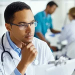35mm portrait, depth of field, a healthcare professional looking thoughtfully at medical test results, with a blurred background suggesting a busy lab or clinic.