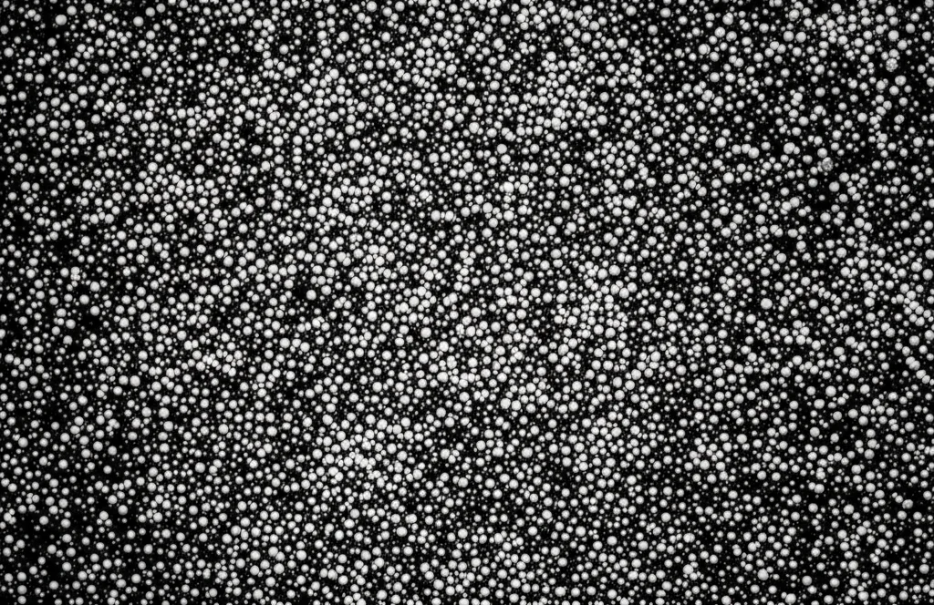 Macro lens, 100mm, high detail, controlled lighting, image showing shimmering magnetic nanoparticles under a microscope, representing the Ho-doped spinel ferrites.