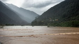 A dramatic wide-angle landscape photograph (10mm) capturing intense rainfall over the mountainous terrain of the North Indian Himalayas, with floodwaters visible in the foreground. Sharp focus, long exposure to emphasize the heavy rain and turbulent atmosphere.