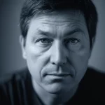 A thoughtful person, 35mm portrait, depth of field, subtle blue and grey duotone, representing the complex experience of advanced Parkinson's.